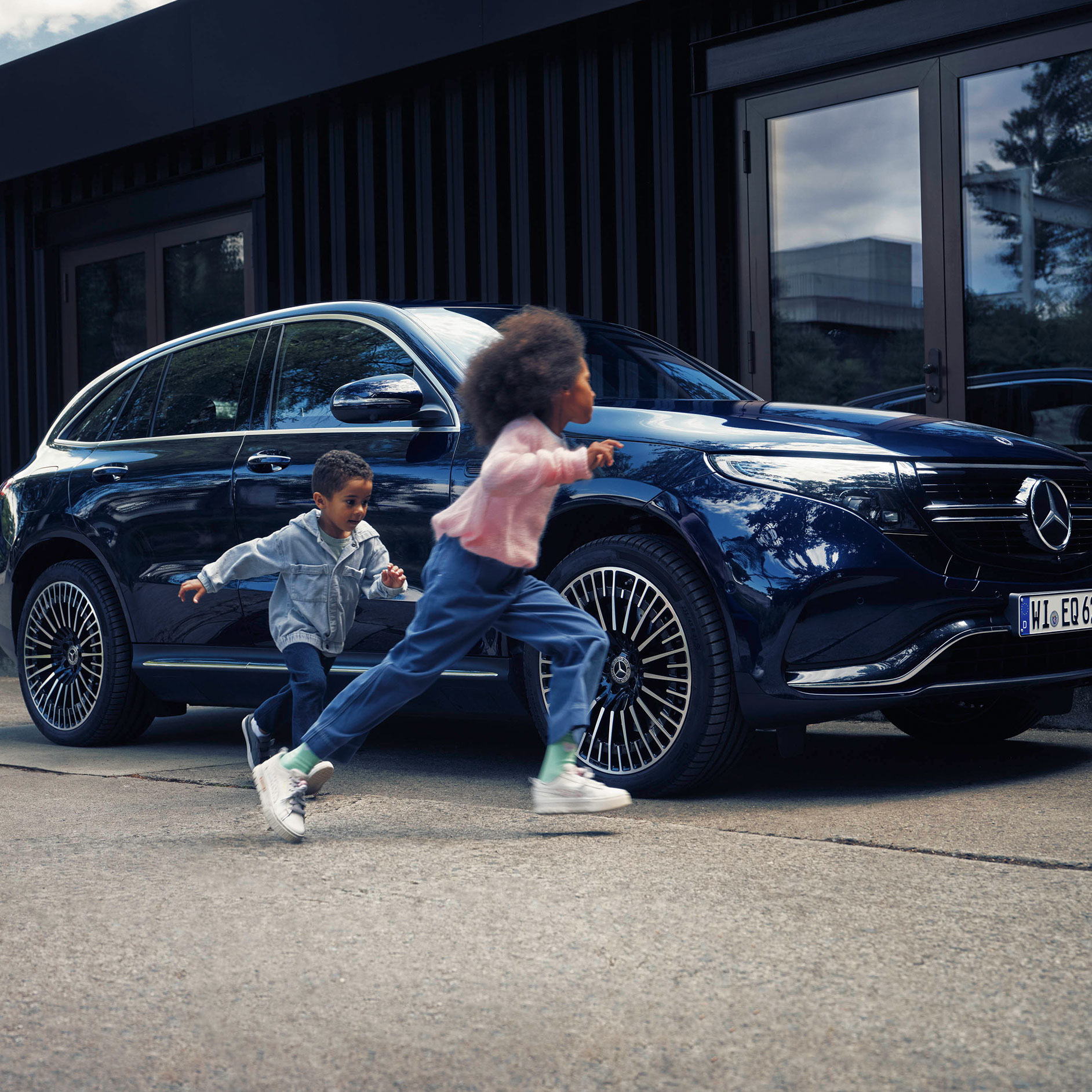 Insurance | Financial Services | Mercedes-Benz Children running next to blue Mercedes-Benz EQC