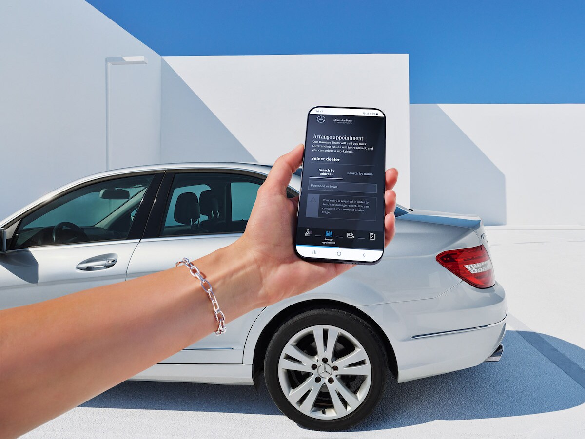 A woman reporting vehicle damage online via her smartphone.