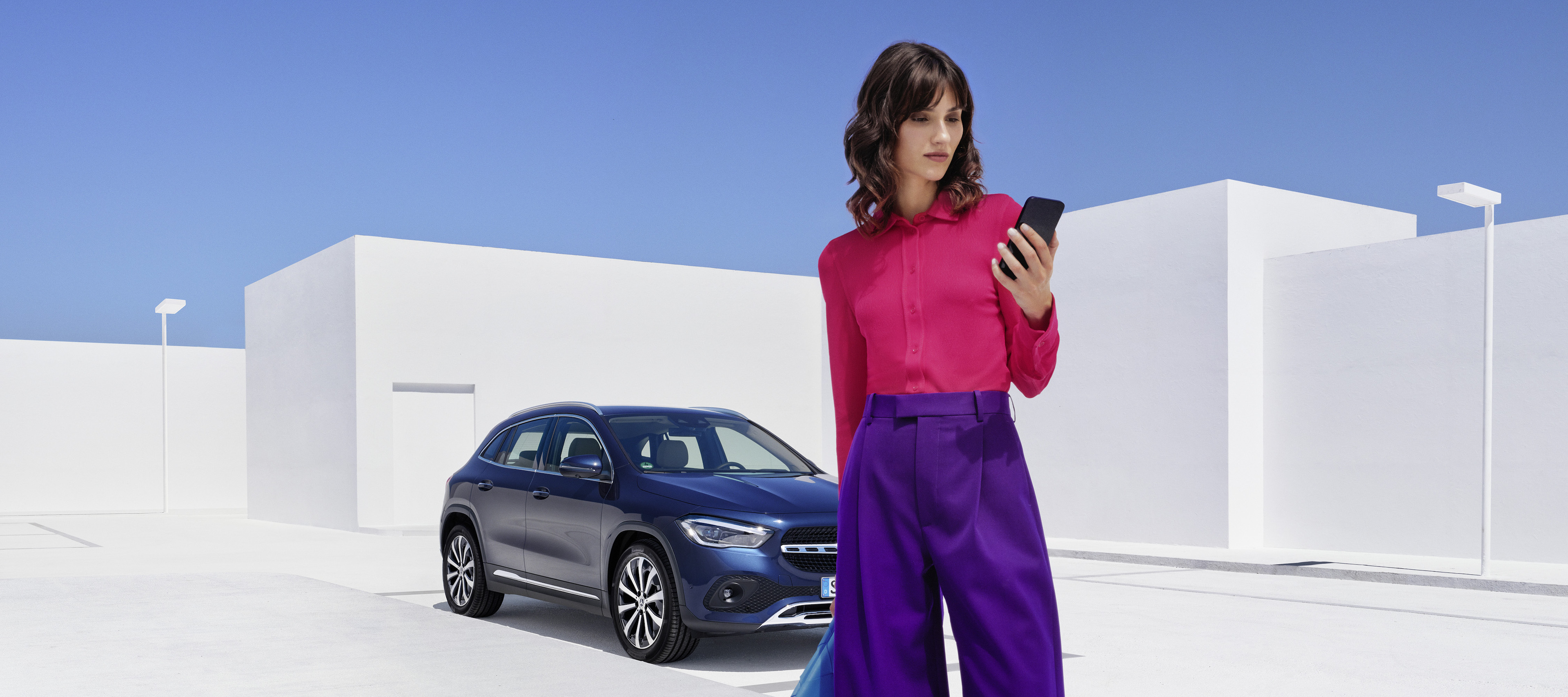 Mercedes-Benz assembly and installation A woman in front of a Mercedes-Benz looking at her smartphone.