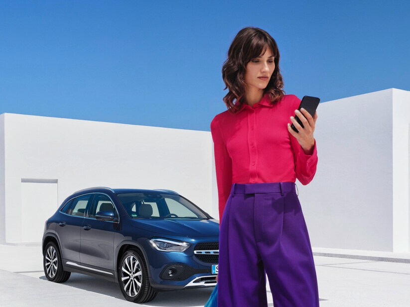 Woman on phone in front of her Mercedes-Benz 