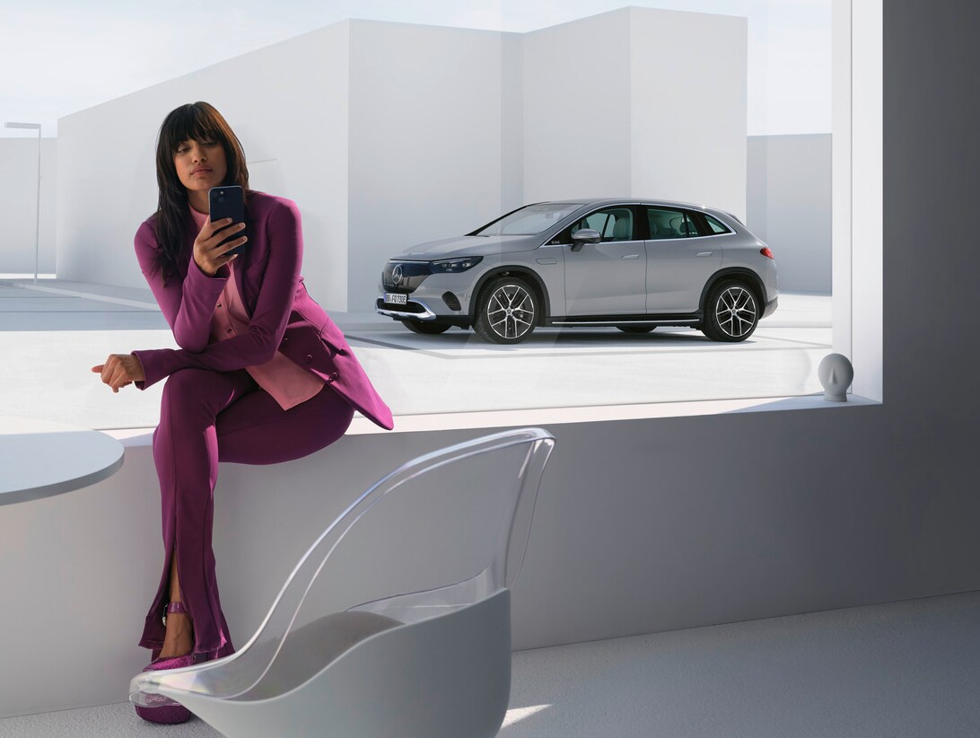 Woman on phone in front of her Mercedes-Benz 