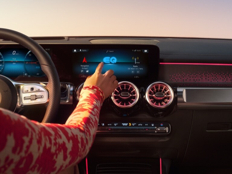 A woman starts the navigation on the screen of the MBUX multimedia system from Mercedes-Benz.
