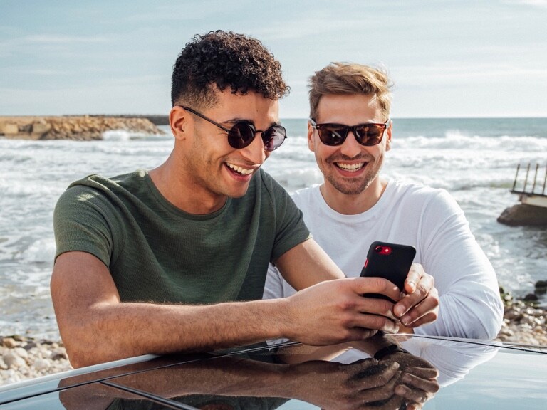 Two men are connected to their Mercedes-Benz via Digital Extras on their smartphones.