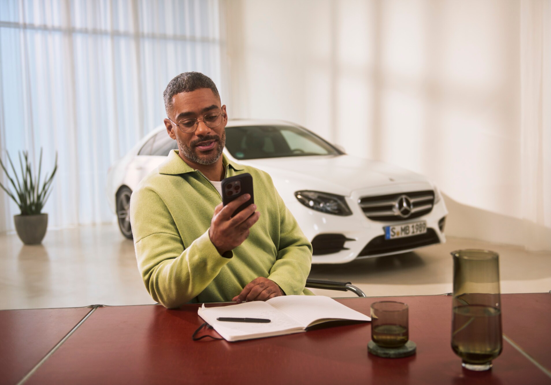 A consultant sitting at a table and looking at their smartphone.