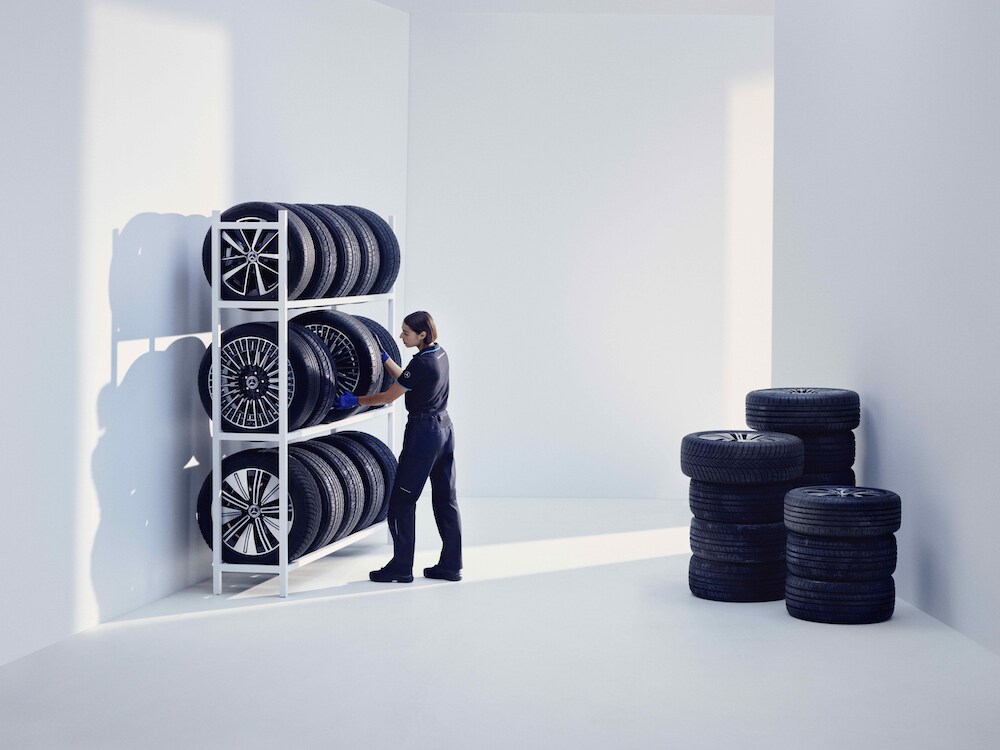 A Mercedes-Benz employee stands in front of some shelves with stored wheels.