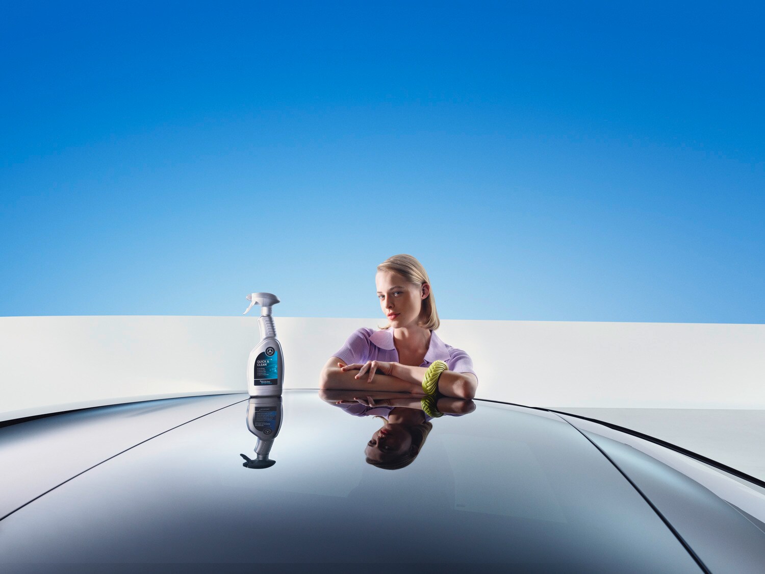 A woman leans on a Mercedes-Benz with cleaning and reconditioning equpiment.