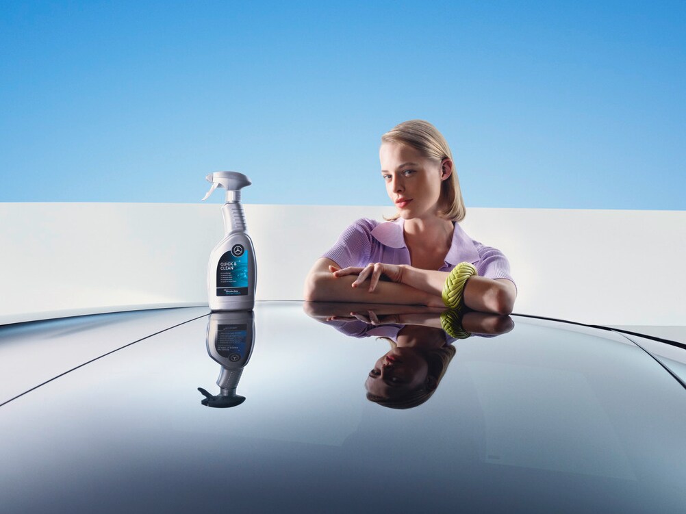 A woman leans on a Mercedes-Benz with cleaning and reconditioning equpiment.
