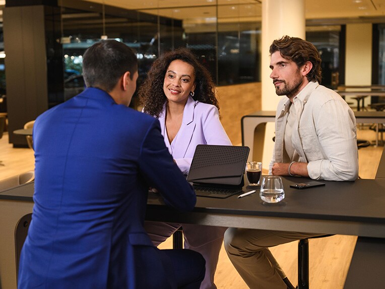 Three people sitting on a table engaging in a discussion.