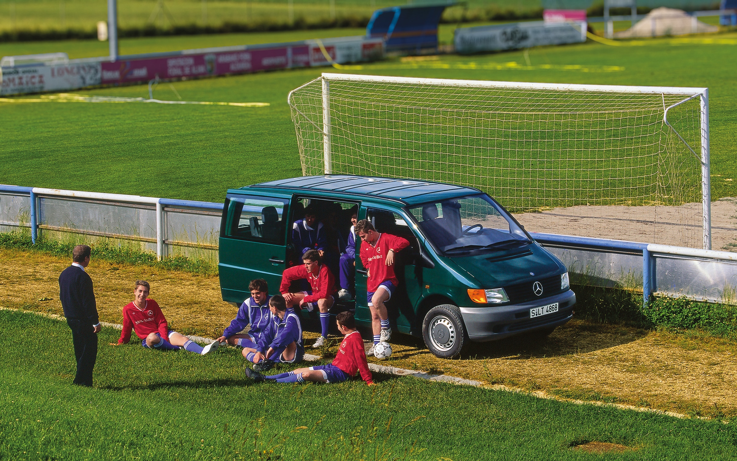 The first generation of Mercedes-Benz Vitos | Commercial Vehicles History | Mercedes-Benz First generation Vito parked beside football field with team players nearby