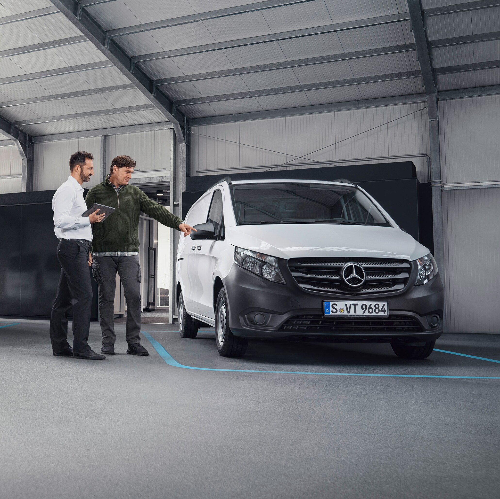 Mercedes-Benz customer support agent with client in a service partner location in front of a van.