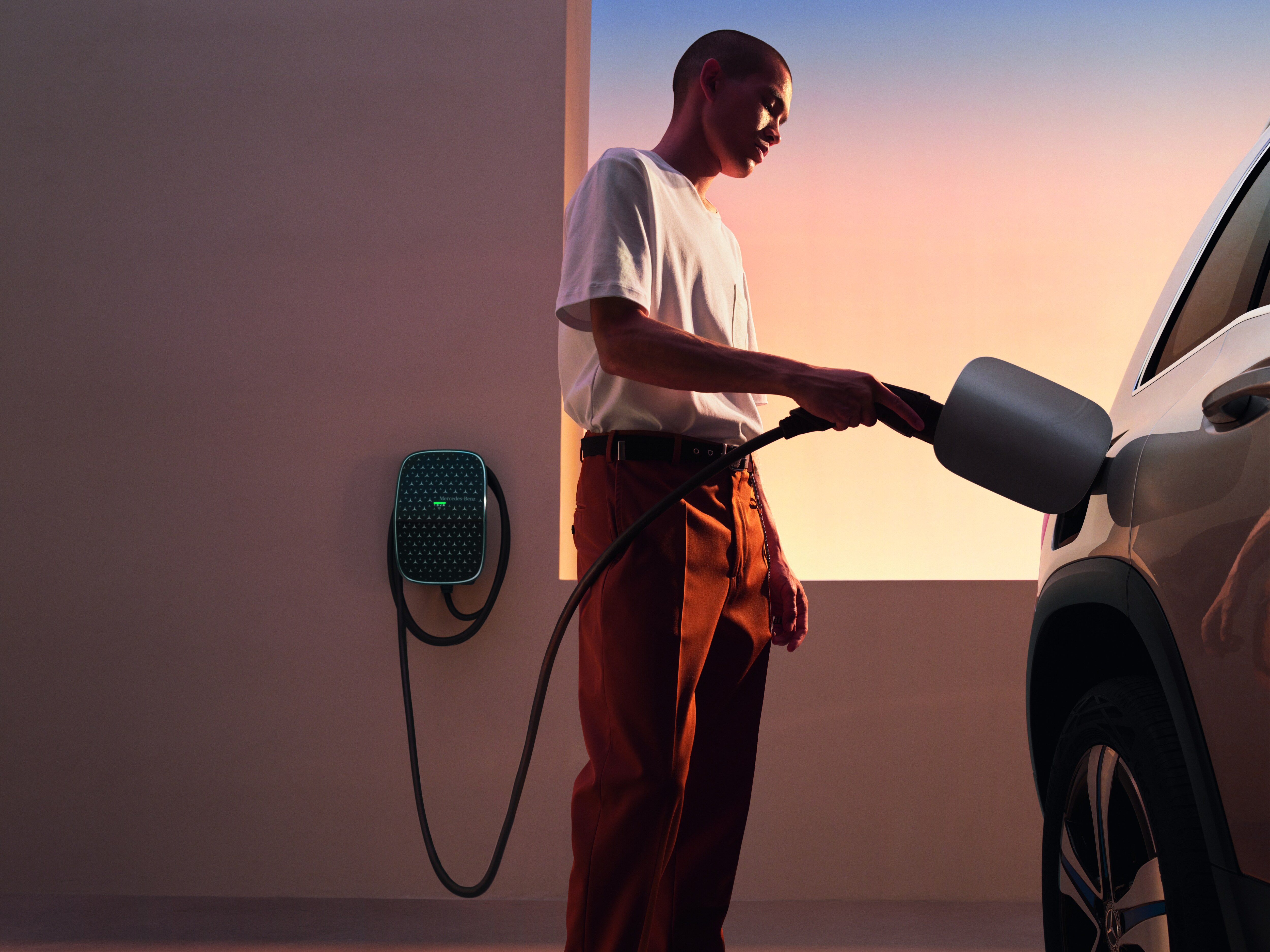 A man using the Mercedes-Benz Wallbox to charge an EV. Overseas model shown.
