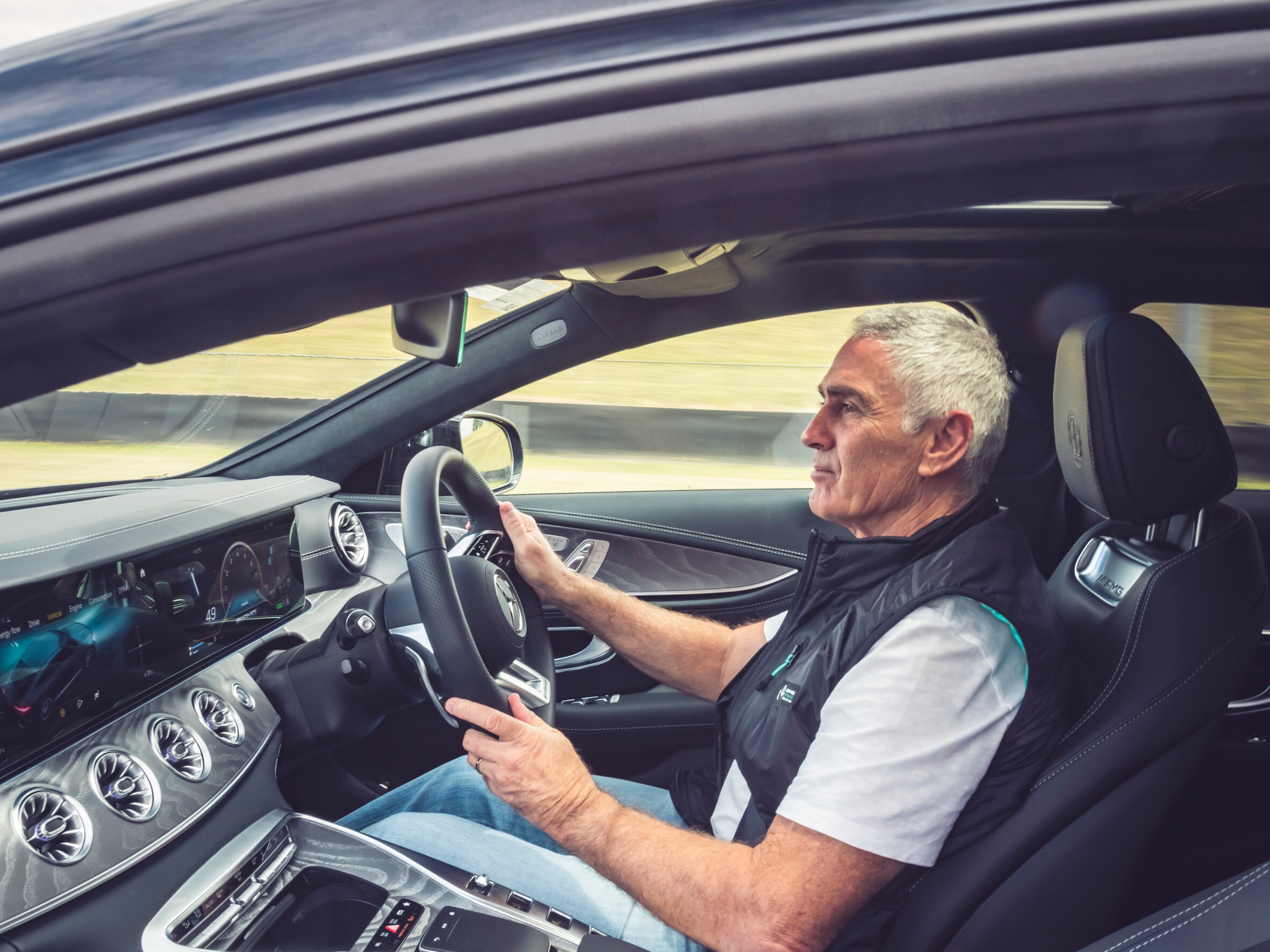 Mick Doohan standing next to a Mercedes-AMG GT 63 S E PERFORMANCE at Sydney Motorsport Park. 