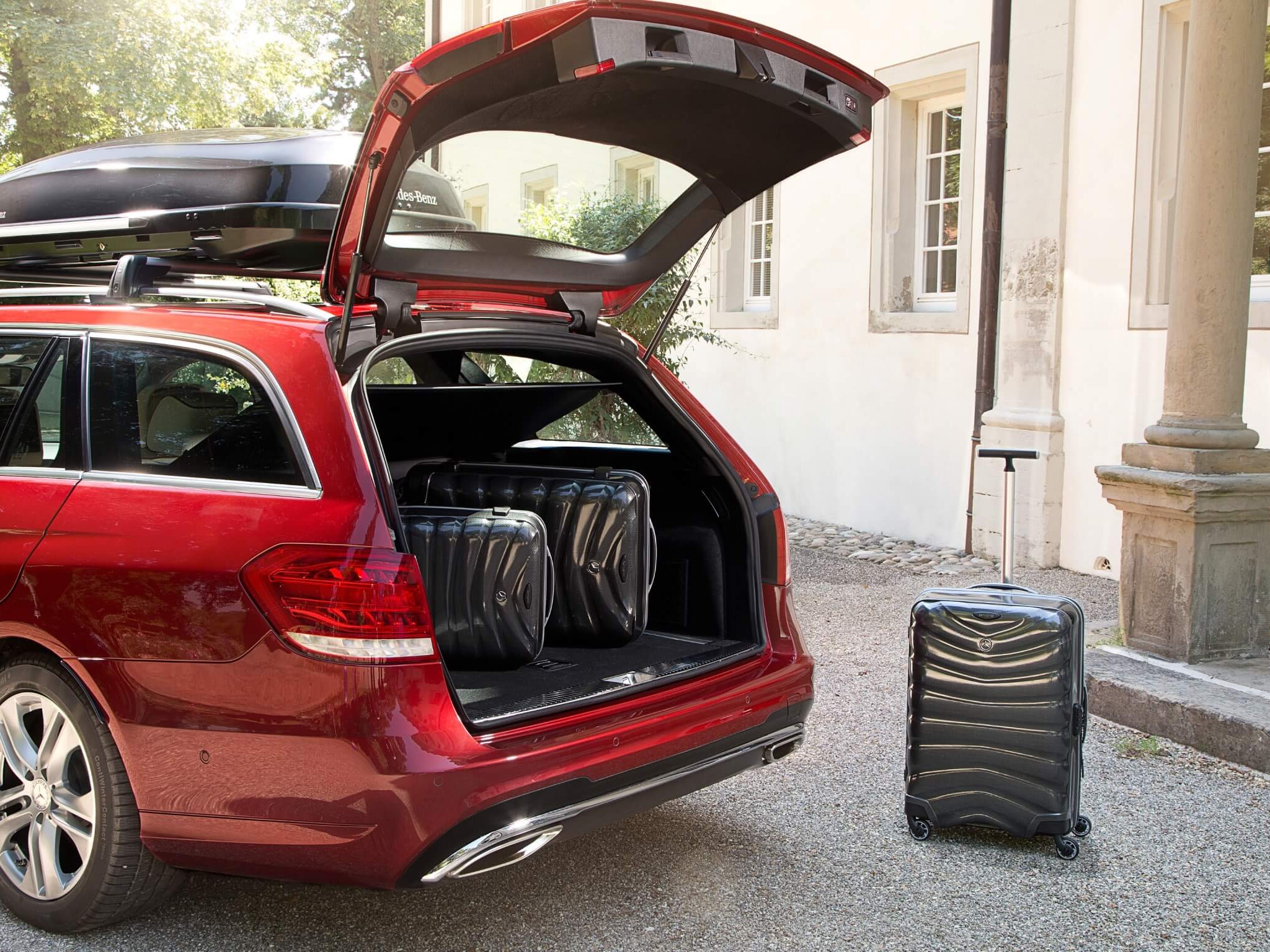 The image shows a Mercedes-Benz with a roof box from Genuine Accessories.